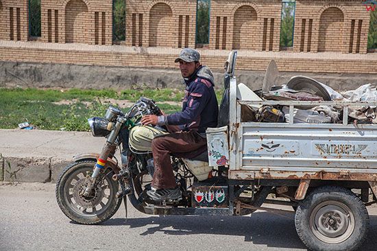 Irak, Hillah (Al Hilla). Robotnik jadacy trojkolowym motocyklem w centrum miasta.
